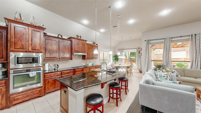 kitchen featuring decorative backsplash, open floor plan, a breakfast bar, stainless steel appliances, and an island with sink