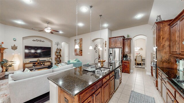 kitchen featuring arched walkways, a sink, appliances with stainless steel finishes, and open floor plan