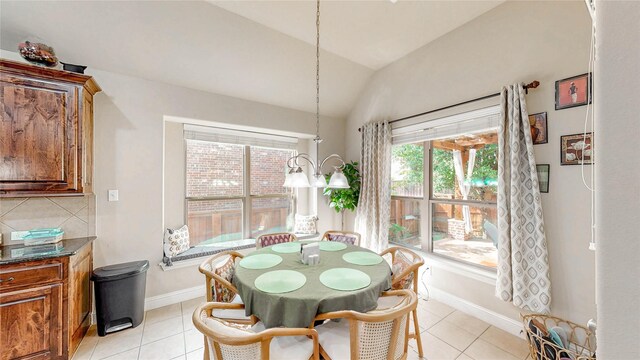 dining room with baseboards, light tile patterned floors, and vaulted ceiling