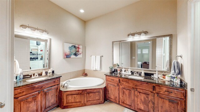 bathroom with a sink, tile patterned floors, a bath, and two vanities