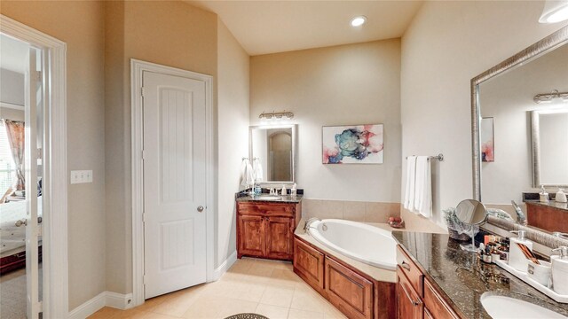 full bath featuring tile patterned flooring, baseboards, a bath, and vanity