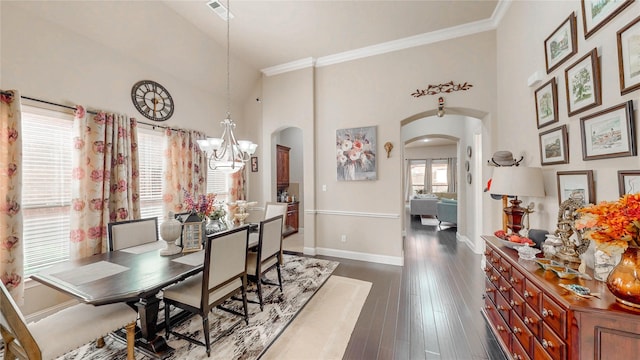 dining space featuring a towering ceiling, crown molding, arched walkways, baseboards, and a notable chandelier