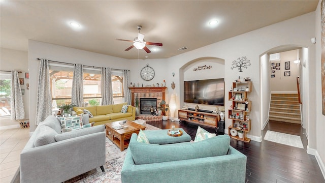 living room with stairs, a ceiling fan, baseboards, and arched walkways