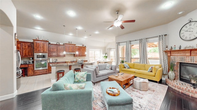 living area featuring recessed lighting, a ceiling fan, light wood finished floors, and a brick fireplace