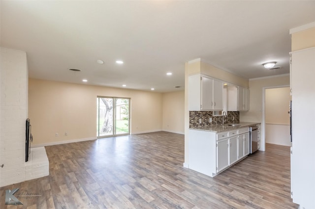 kitchen with stainless steel dishwasher, decorative backsplash, white cabinetry, a sink, and light wood finished floors