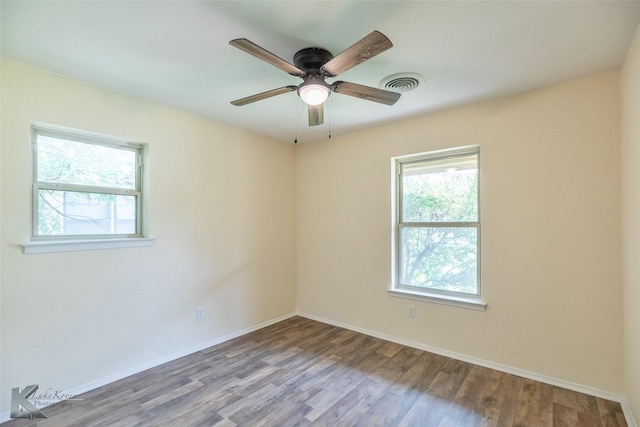 spare room featuring ceiling fan, visible vents, a healthy amount of sunlight, and wood finished floors