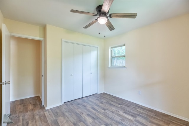 unfurnished bedroom featuring baseboards, ceiling fan, a closet, and wood finished floors