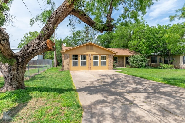 ranch-style home featuring brick siding, fence, driveway, and a front yard