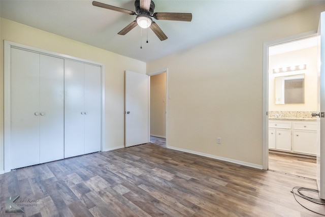 unfurnished bedroom with a ceiling fan, wood finished floors, baseboards, a closet, and connected bathroom