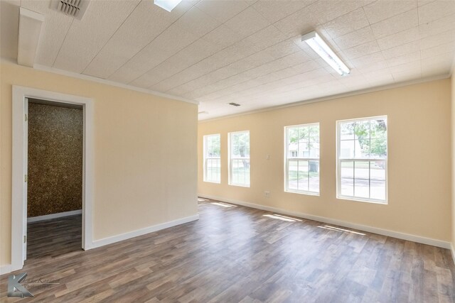 spare room with baseboards, visible vents, ornamental molding, and wood finished floors