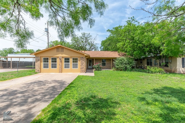 ranch-style home with brick siding, driveway, fence, and a front yard