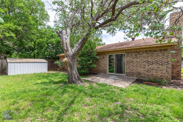 rear view of property featuring a lawn, fence, an outbuilding, and a shed