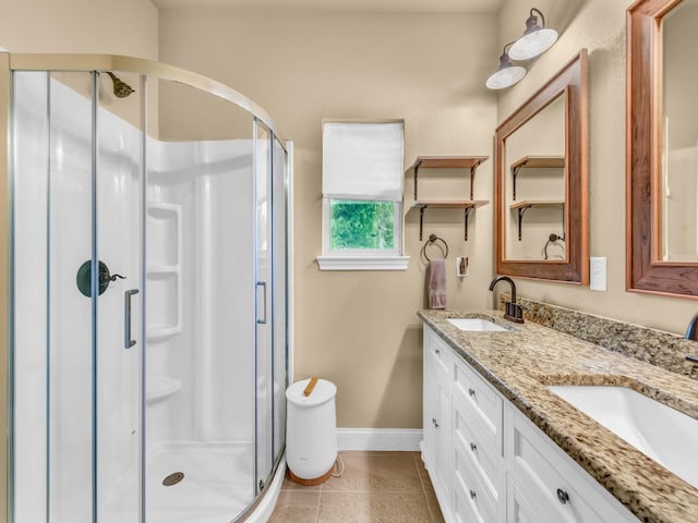 bathroom featuring baseboards, a sink, a stall shower, and double vanity