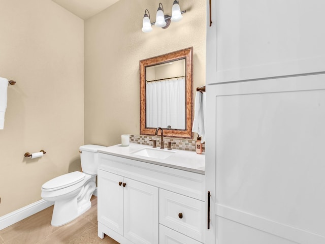 bathroom with vanity, baseboards, backsplash, and toilet