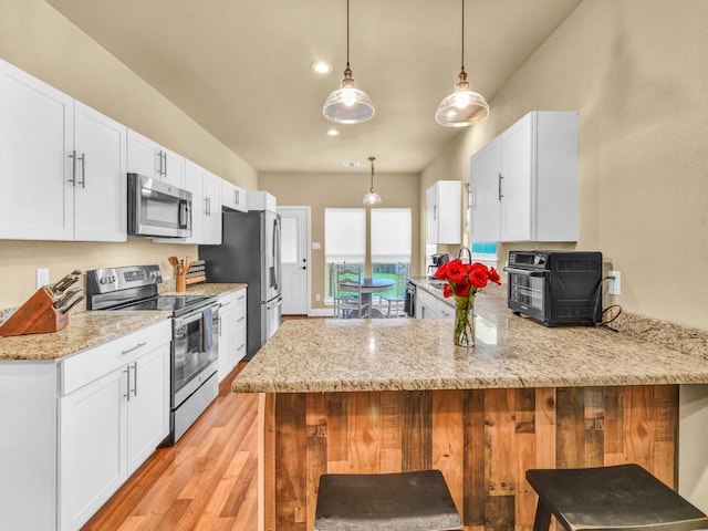 kitchen featuring light wood-style floors, appliances with stainless steel finishes, a peninsula, and white cabinetry