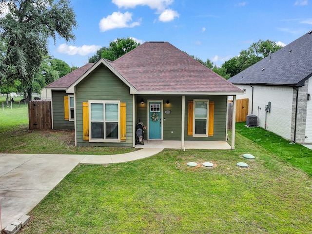 rear view of property featuring a yard, fence, cooling unit, and a shingled roof