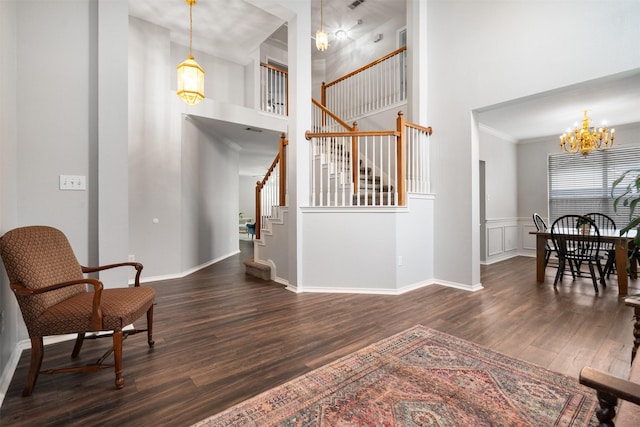 interior space featuring stairway, a high ceiling, an inviting chandelier, and dark wood-type flooring