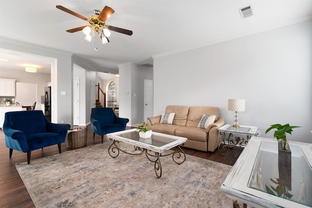 living area with a ceiling fan, dark wood-style flooring, visible vents, crown molding, and stairway