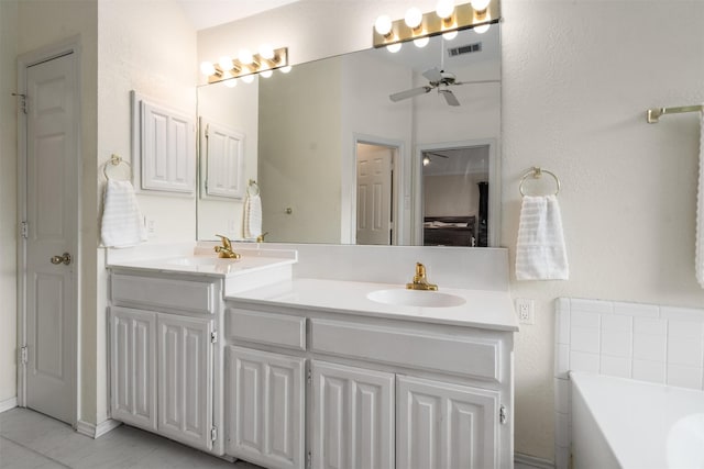 bathroom with double vanity, a ceiling fan, a sink, and a garden tub