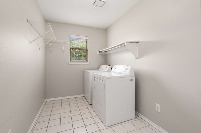 clothes washing area featuring light tile patterned floors, laundry area, washing machine and dryer, and baseboards