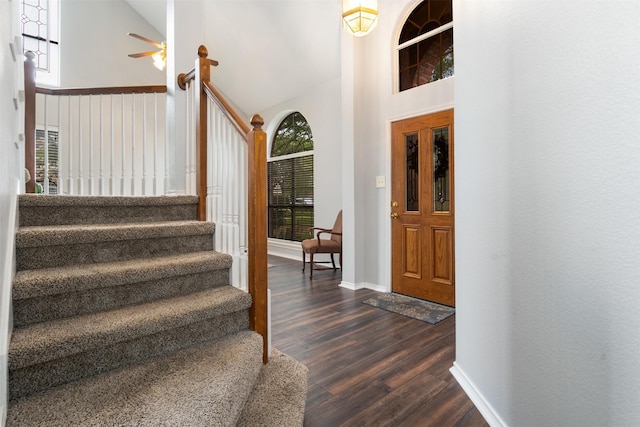 entryway featuring a high ceiling, ceiling fan, baseboards, dark wood-style floors, and stairway