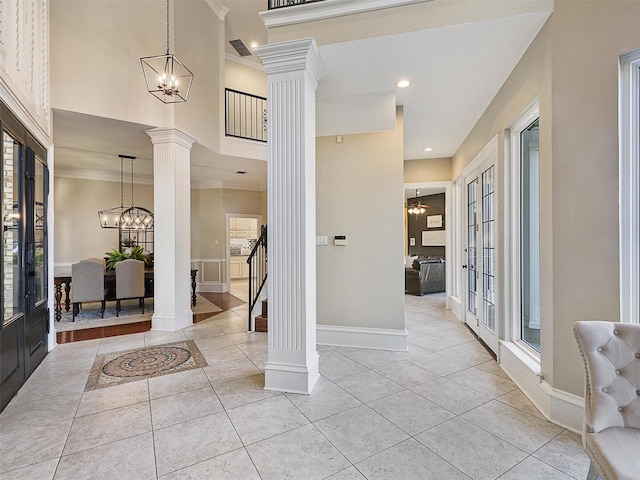 entrance foyer with ornate columns, a chandelier, light tile patterned flooring, crown molding, and baseboards