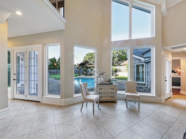doorway to outside featuring a high ceiling, tile patterned flooring, and baseboards