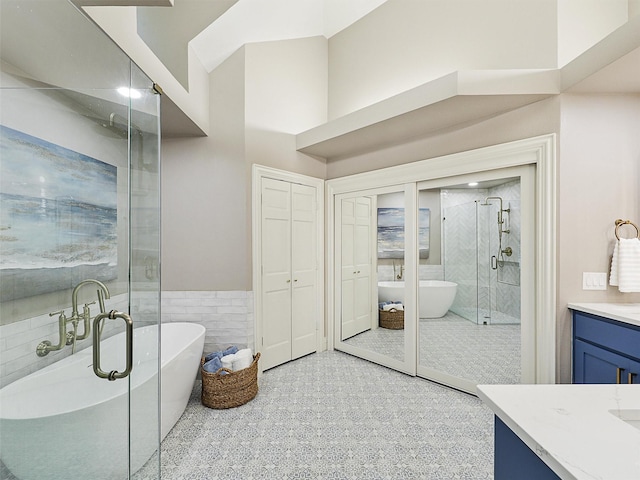 bathroom with vanity, tile walls, a shower stall, a wainscoted wall, and a freestanding tub