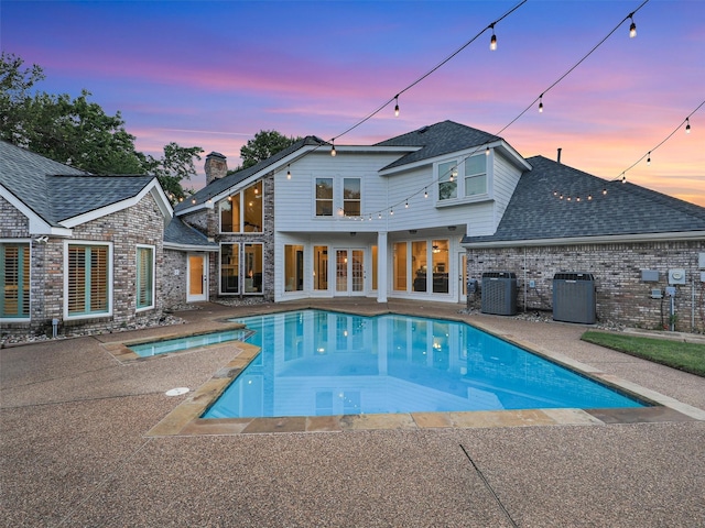 swimming pool with a patio area and central AC unit