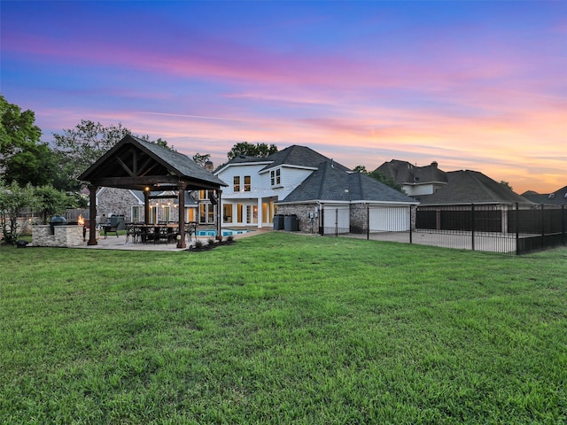 back of house at dusk with a gazebo, a garage, a patio area, and brick siding
