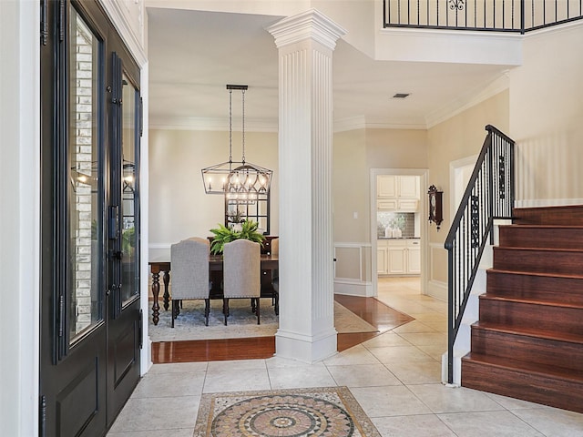 entrance foyer featuring decorative columns, stairway, crown molding, light tile patterned floors, and plenty of natural light
