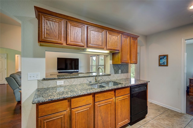 kitchen with light stone counters, tasteful backsplash, a sink, and dishwasher