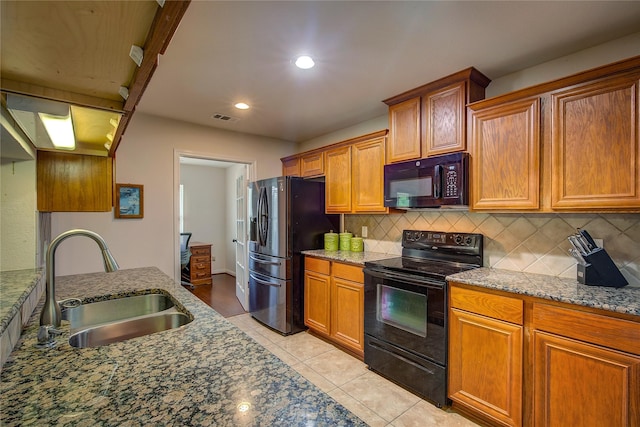 kitchen with a sink, light tile patterned floors, tasteful backsplash, visible vents, and black appliances