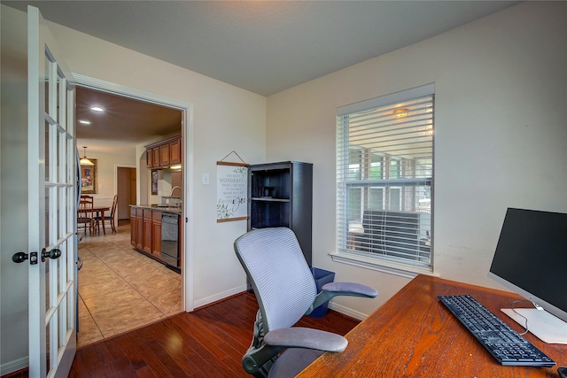 office featuring baseboards, a sink, and light wood-style floors