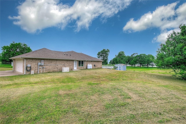 view of yard with a storage shed, an outdoor structure, driveway, and a garage