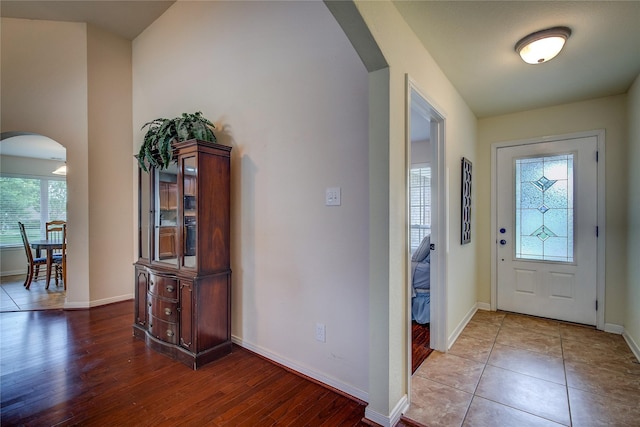 foyer featuring baseboards, arched walkways, and wood finished floors