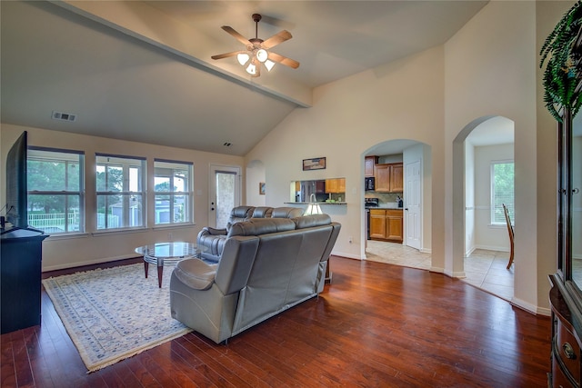 living room with visible vents, a ceiling fan, wood finished floors, beamed ceiling, and arched walkways