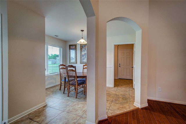 dining space with arched walkways, baseboards, wood finished floors, and visible vents