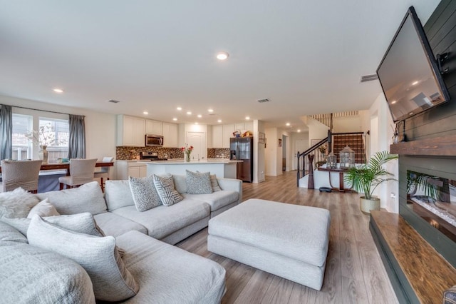 1016 Webb Ave, Aubrey, TX 76227 - living room featuring light wood finished floors, a glass covered fireplace, recessed lighting, visible vents, and stairway