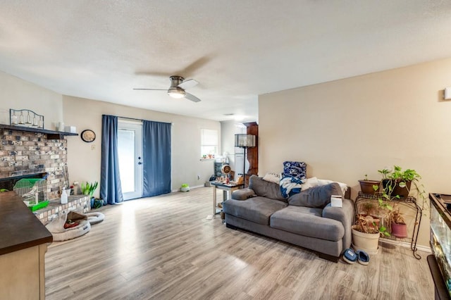 living room featuring baseboards, ceiling fan, a fireplace, and wood finished floors