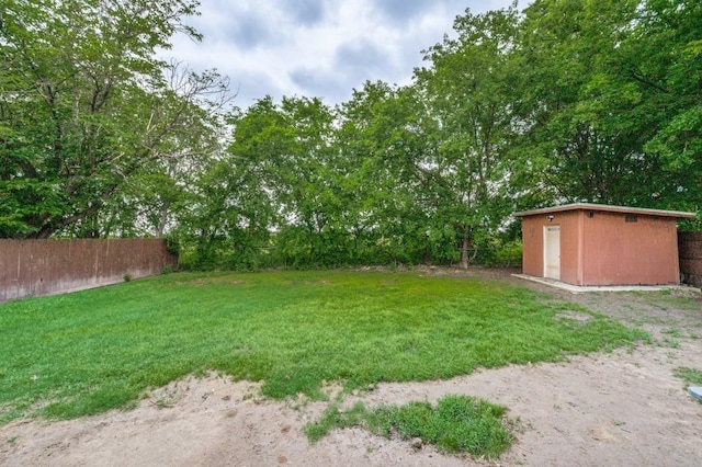 view of yard featuring a storage shed, fence, and an outdoor structure