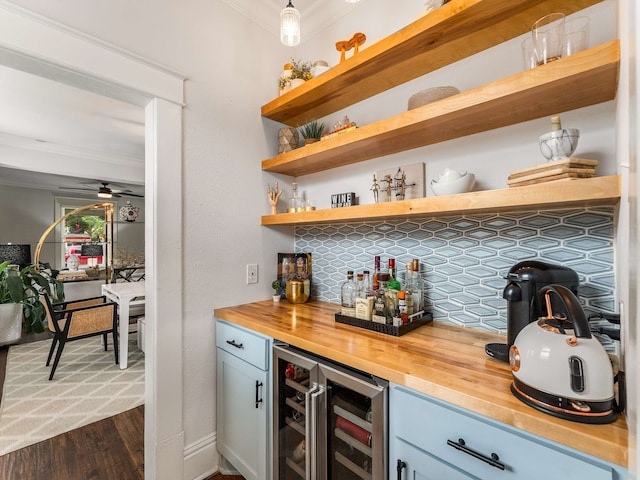 bar with bar, a ceiling fan, dark wood finished floors, wine cooler, and ornamental molding