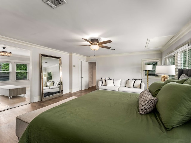 bedroom with crown molding, baseboards, wood finished floors, and visible vents