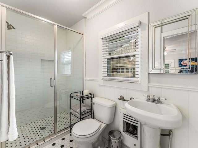 bathroom featuring wainscoting, toilet, ceiling fan, and a shower stall