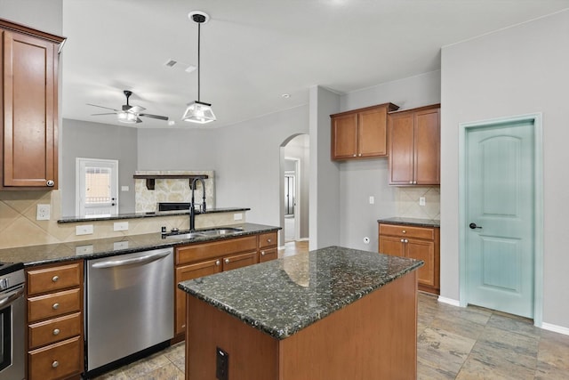 kitchen featuring brown cabinets, a sink, arched walkways, a ceiling fan, and stainless steel dishwasher