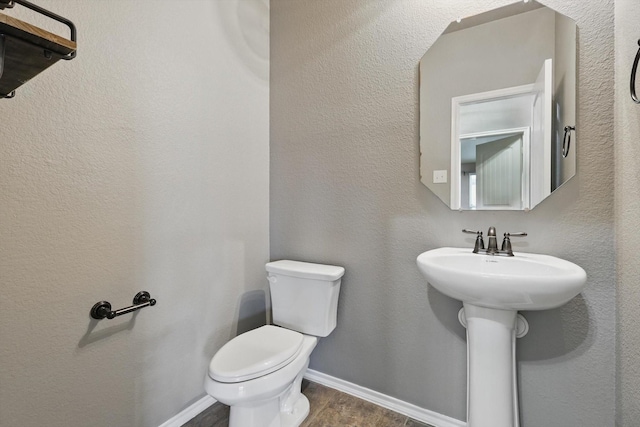 bathroom featuring a sink, baseboards, toilet, and wood finished floors
