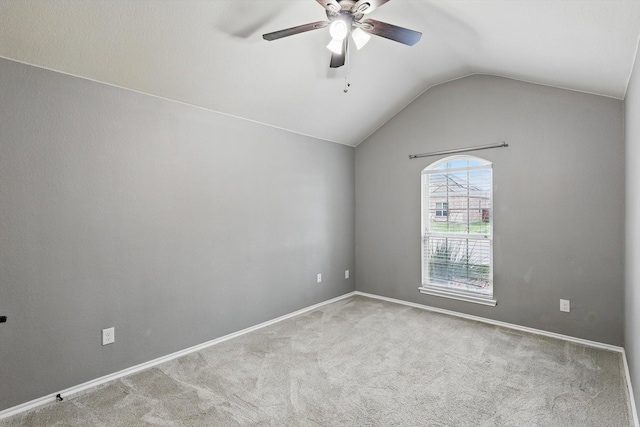carpeted empty room featuring baseboards, ceiling fan, and vaulted ceiling