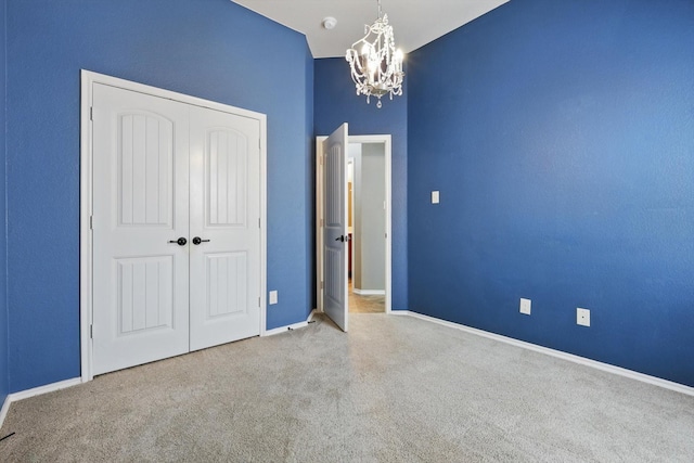unfurnished bedroom featuring carpet flooring, baseboards, a notable chandelier, and a closet