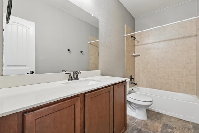 bathroom featuring vanity, a textured wall, shower / bathtub combination, and toilet