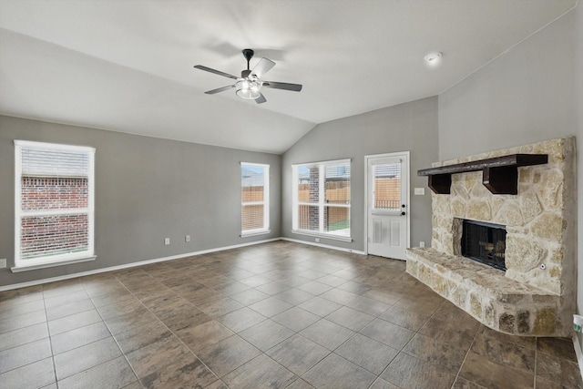 unfurnished living room featuring lofted ceiling, a fireplace, baseboards, ceiling fan, and dark tile patterned floors